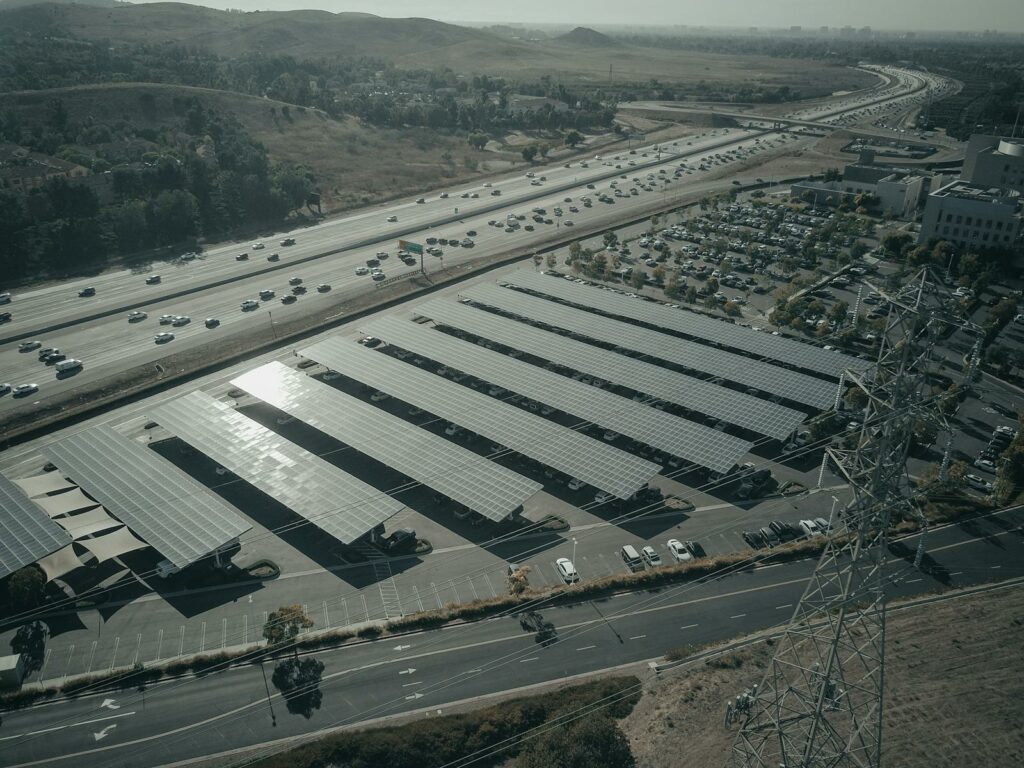 Aerial photo of a solar farm beside a busy highway with cars and power lines.