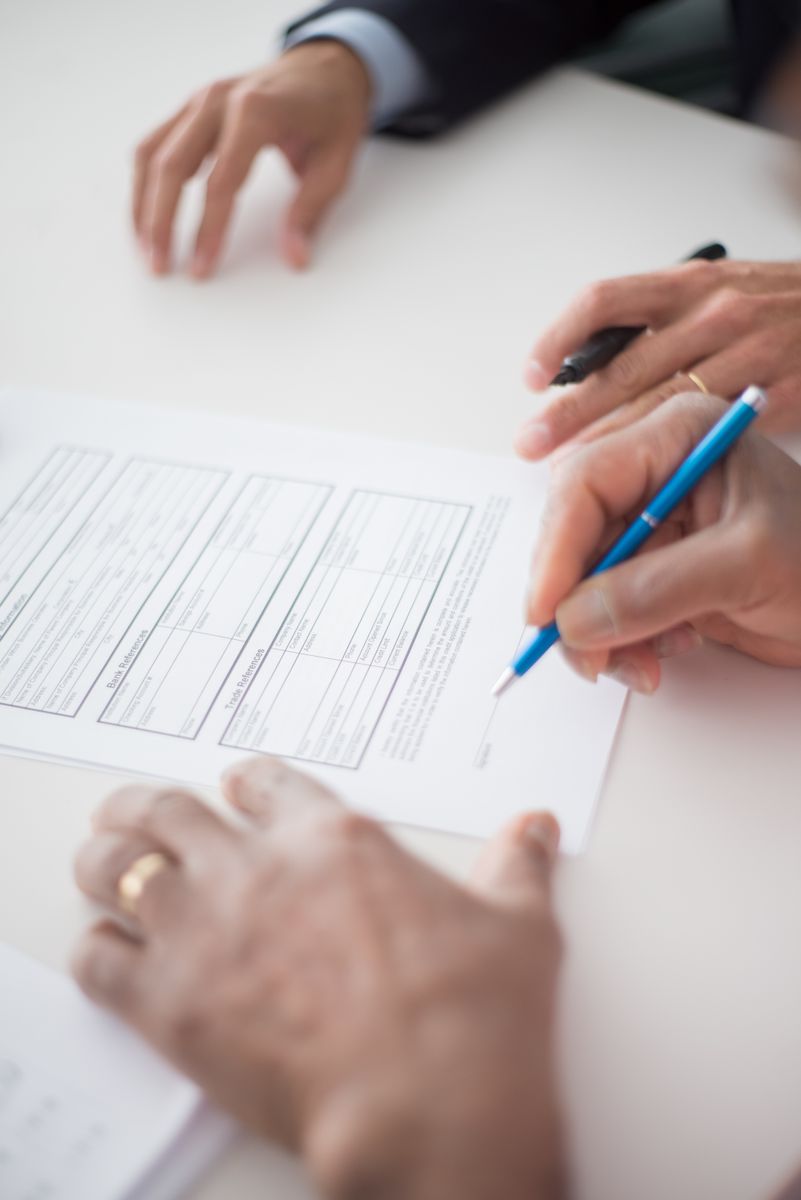 Close-up of hands signing a business document on a white surface with a pen.